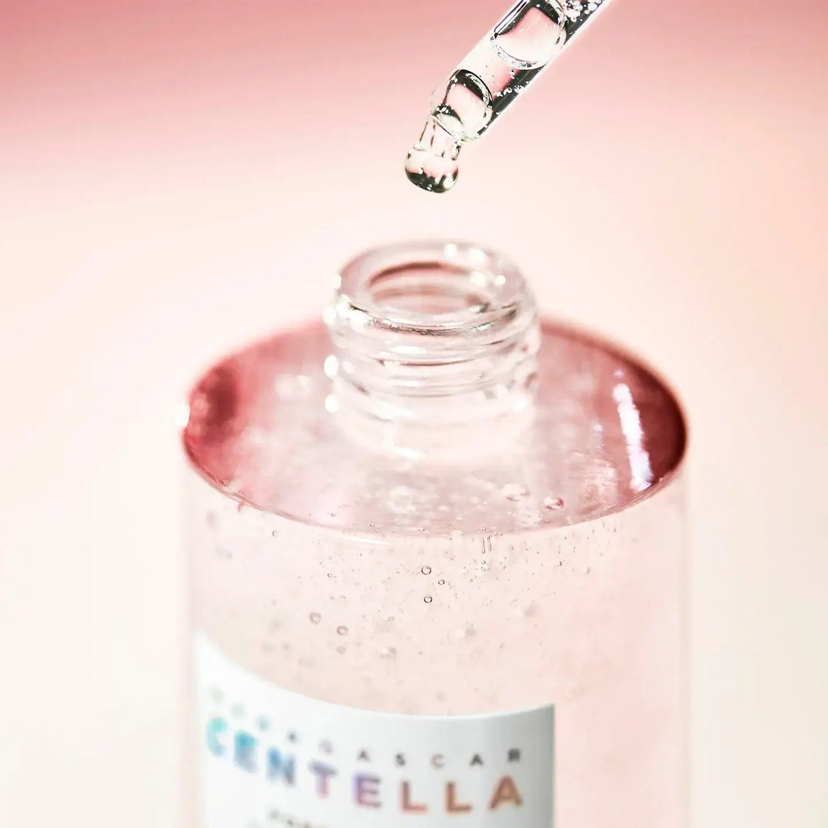 Close-up of SKIN1004 Madagascar Centella ampoule bottle and dropper, showcasing its pink liquid formulation.
