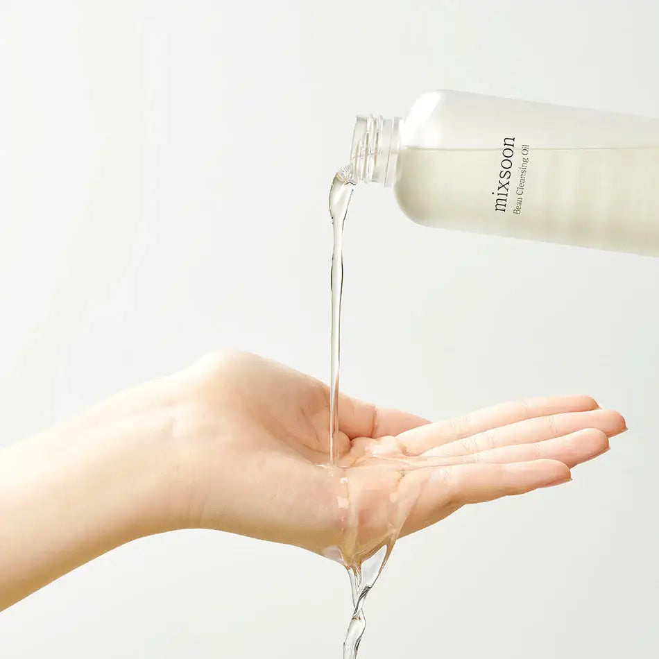 Pouring Mixsoon Bean Cleansing Oil into a hand, showcasing its lightweight texture for gentle cleansing.