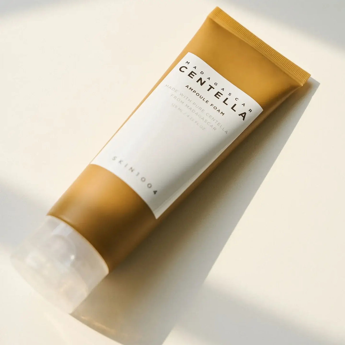 SKIN1004 Madagascar Centella Ampoule Foam tube on a light surface, promoting thorough facial cleansing and skin soothing.