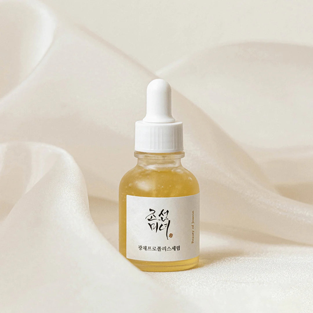 Beauty of Joseon Glow Serum Propolis Niacinamide in a clear dropper bottle on silky fabric.