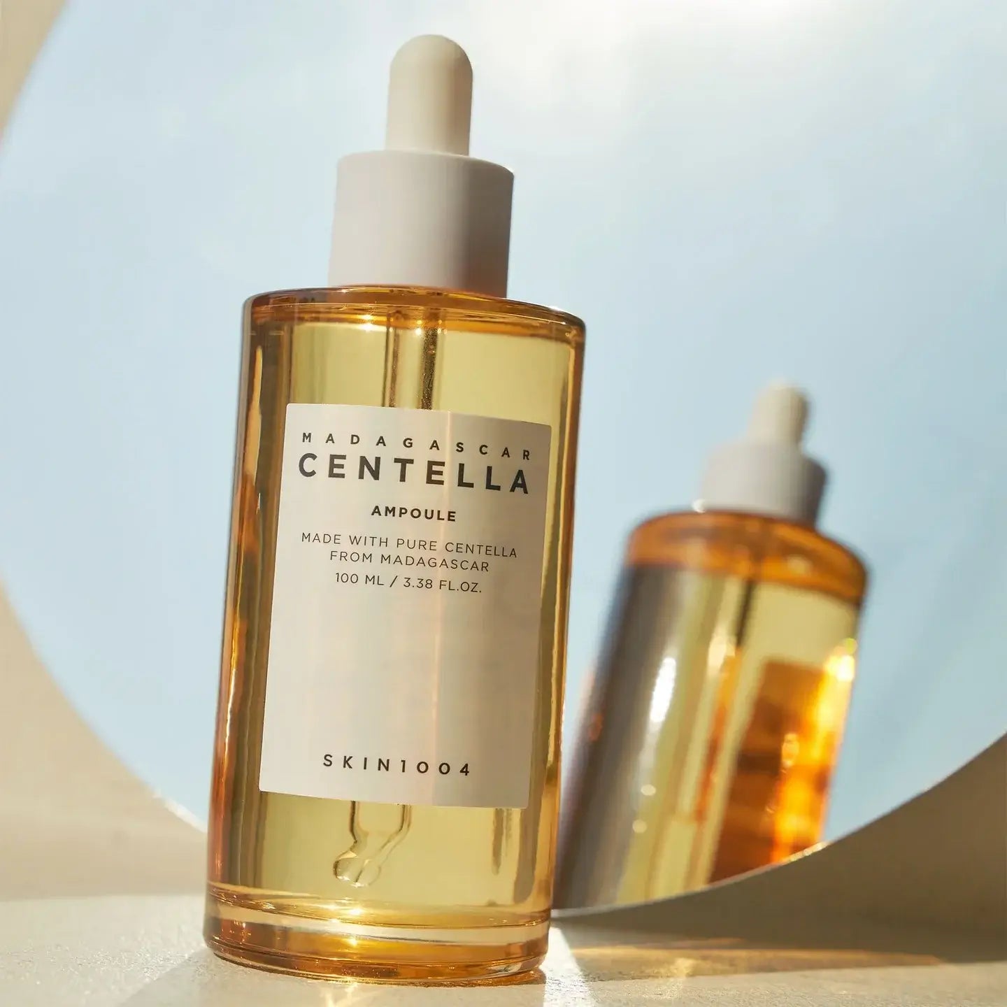 SKIN1004 Madagascar Centella Ampoule 100ml bottle reflecting in mirror for skincare benefits.