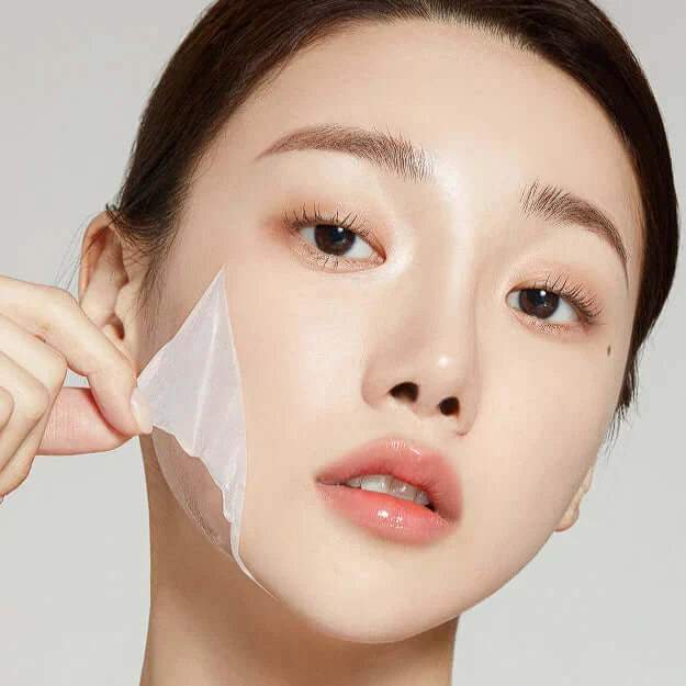 Close-up of a woman peeling off a Medicube Collagen Night Wrapping Mask, showcasing skin hydration and glow.