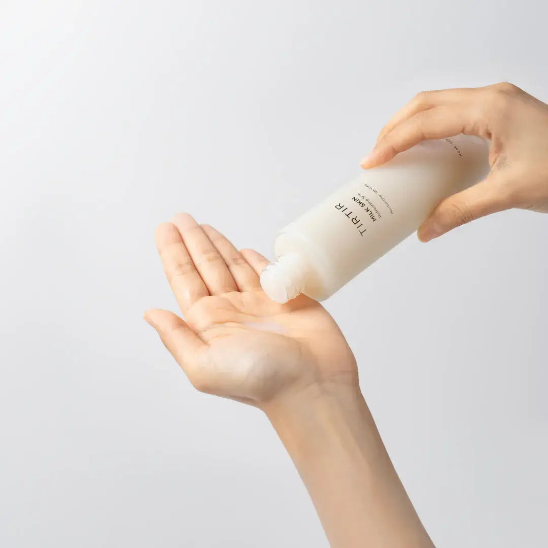 Hand dispensing TIRTIR Milk Skin Toner, a vegan toner for hydration, radiance, and skin barrier support.