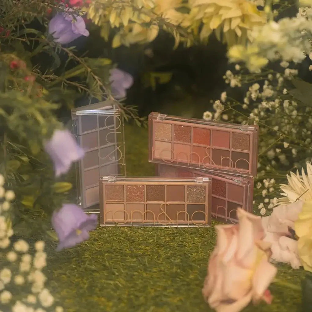rom&nd Better Than Palette Secret Garden featuring four makeup palettes surrounded by vibrant flowers.