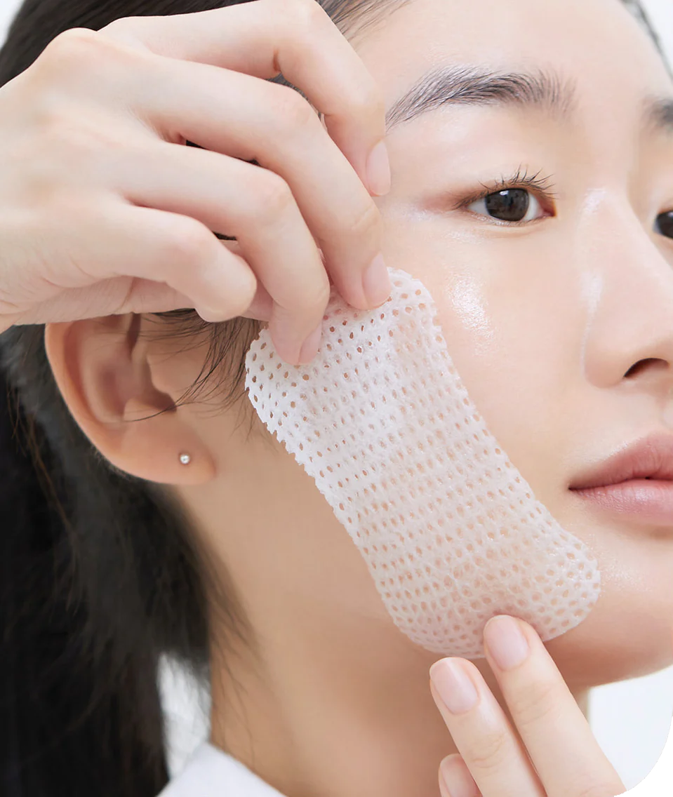 A close-up of a person applying Mediheal's Retinol Collagen Lifting Pad to their face for firmer skin.